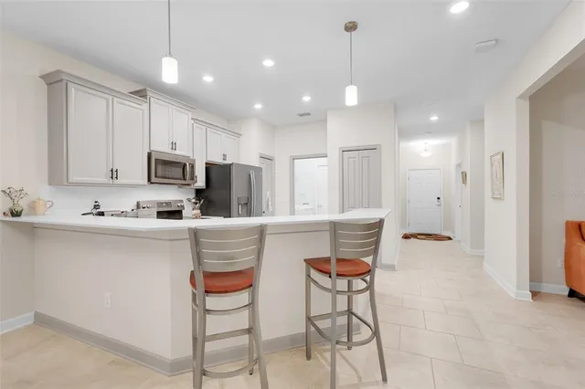 a kitchen with kitchen island granite countertop a stove a sink a refrigerator and white cabinets with wooden floor