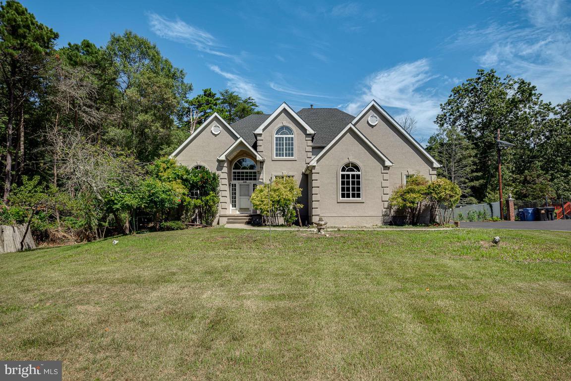 a view of a house with a big yard and large trees