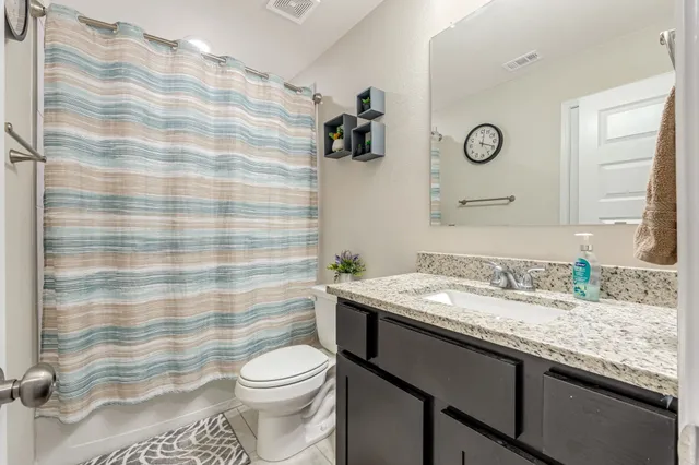 a bathroom with a granite countertop sink a toilet and a shower