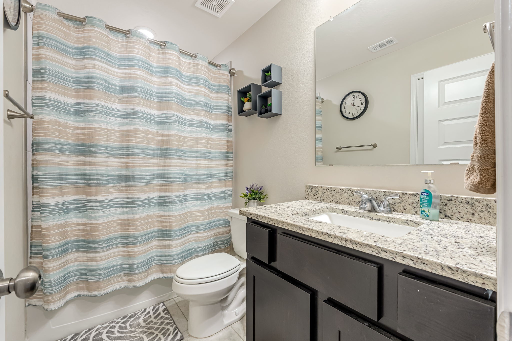 1946 Chief Street Bryan, TX 77807 - Photo 22 of 30 a bathroom with a granite countertop sink a toilet and a shower curtain