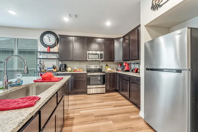 a kitchen with stainless steel appliances granite countertop a refrigerator a stove and a sink