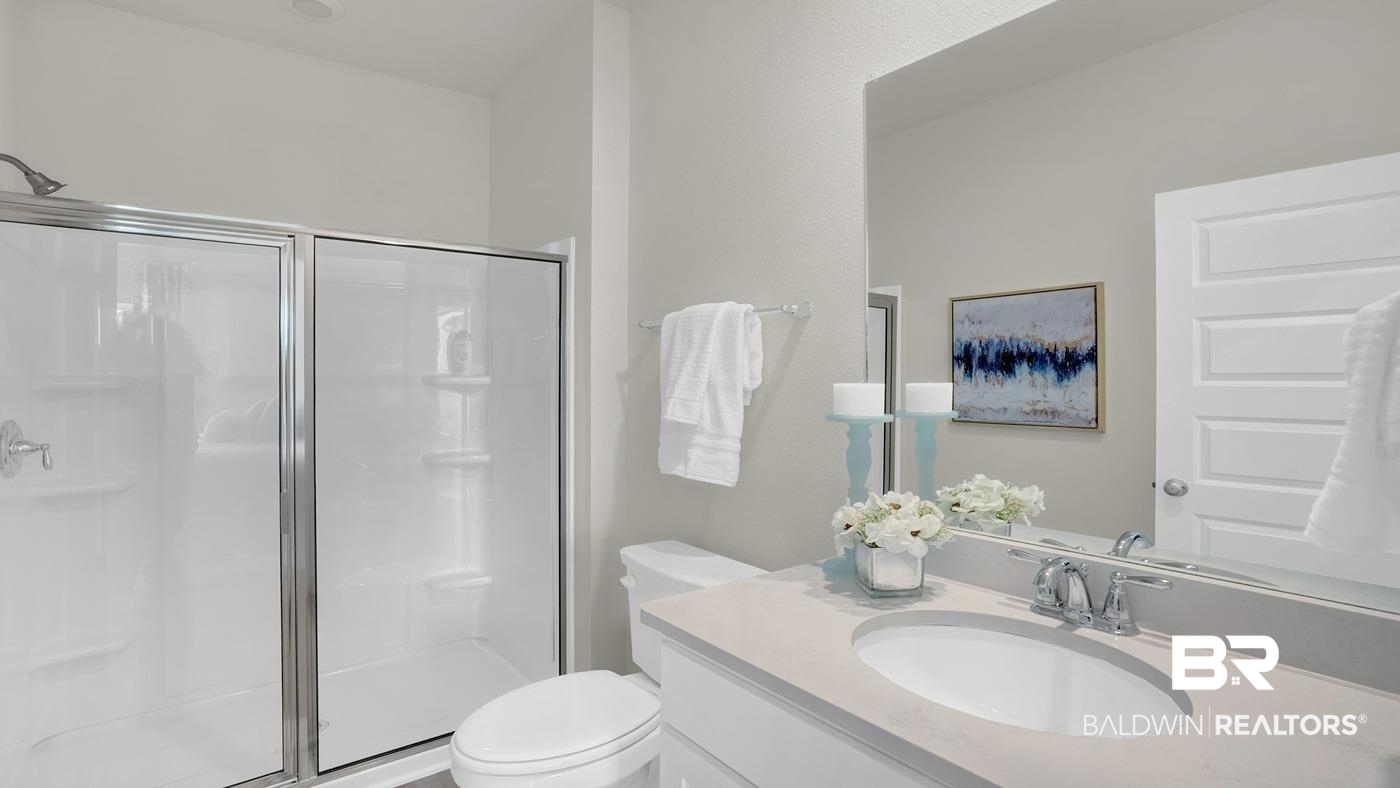 13312 Shea Circle Foley, AL 36535 - Photo 16 of 17 Bathroom featuring a glass-enclosed shower with a chrome showerhead, a white toilet, and a vanity with a light-toned countertop and an undermount sink