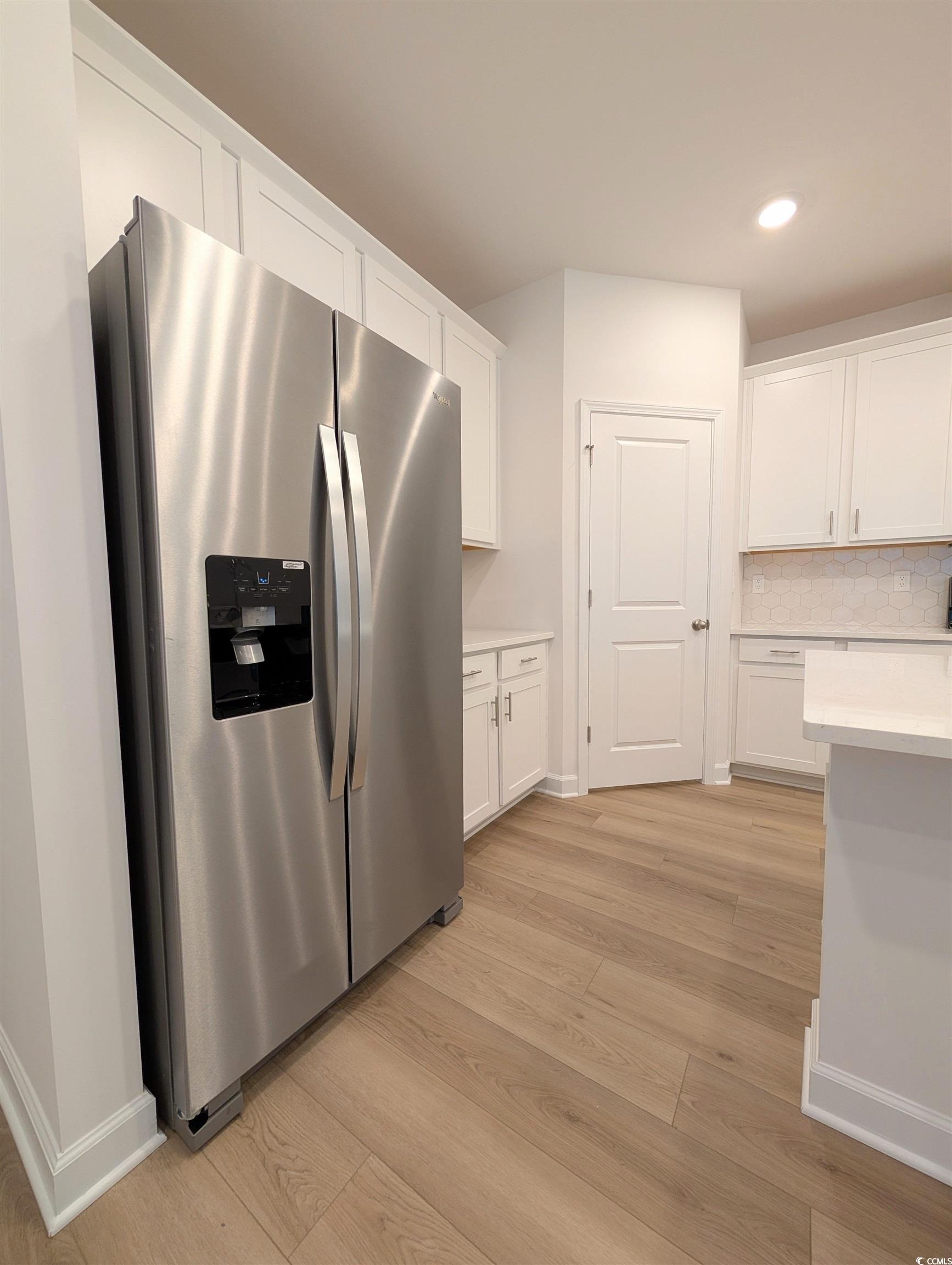 1109 Lauryn Oak Loop Longs, SC 29568 - Photo 8 of 40 Kitchen with stainless steel fridge with ice dispenser, white cabinetry, tasteful backsplash, light wood-type flooring, and recessed lighting
