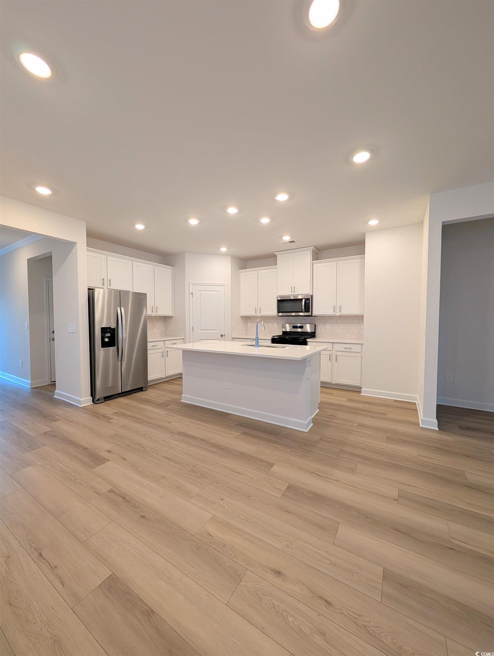1109 Lauryn Oak Loop Longs, SC 29568 - Photo 10 of 40 Kitchen with appliances with stainless steel finishes, white cabinets, an island with sink, light wood-style flooring, and recessed lighting