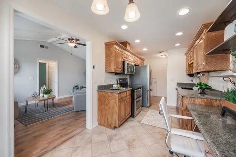 a large kitchen with stainless steel appliances kitchen island granite countertop a table and chairs in it