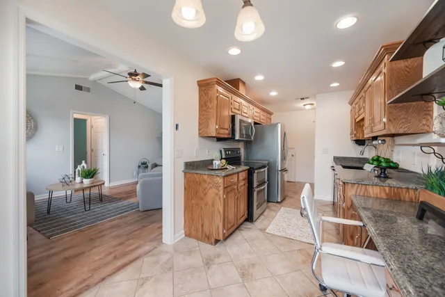 a large kitchen with stainless steel appliances kitchen island granite countertop a table and chairs in it