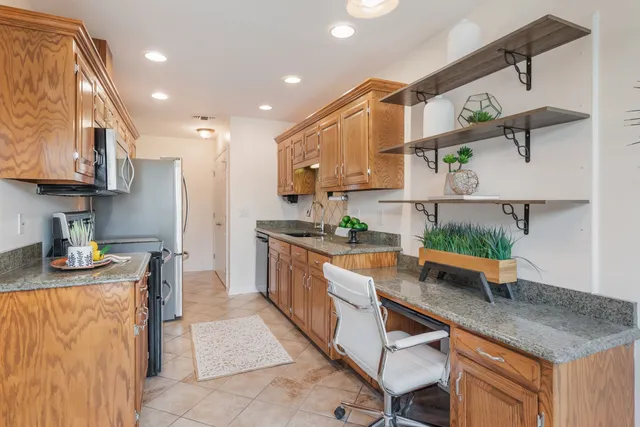 a kitchen with stainless steel appliances granite countertop a sink a stove and a wooden cabinets