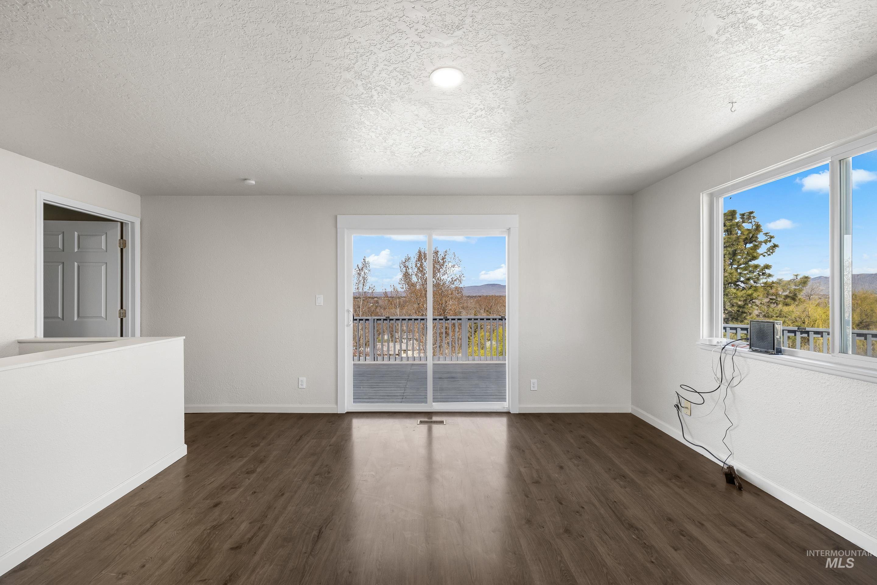 10294 West Fox Ridge Drive Boise, ID 83709 - Photo 14 of 50 Empty room with dark wood-style flooring and a textured ceiling