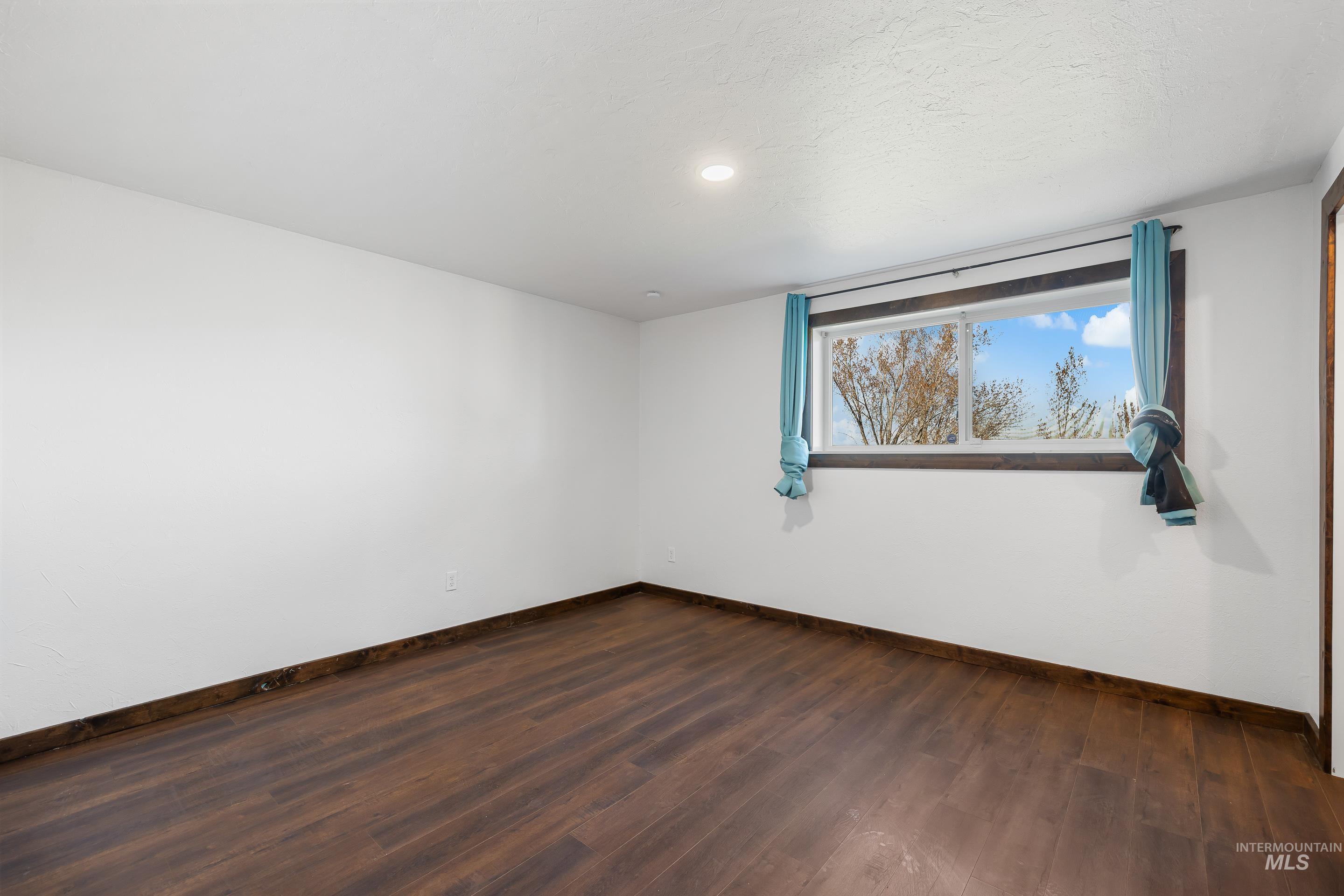 10294 West Fox Ridge Drive Boise, ID 83709 - Photo 27 of 50 Spare room featuring dark wood-style floors and baseboards