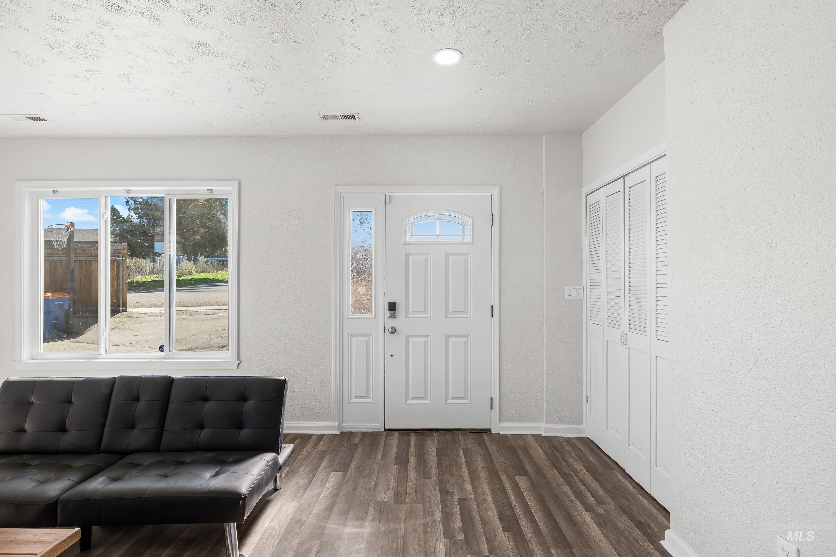 10294 West Fox Ridge Drive Boise, ID 83709 - Photo 5 of 50 Entryway featuring dark wood-style floors, healthy amount of natural light, and a textured ceiling