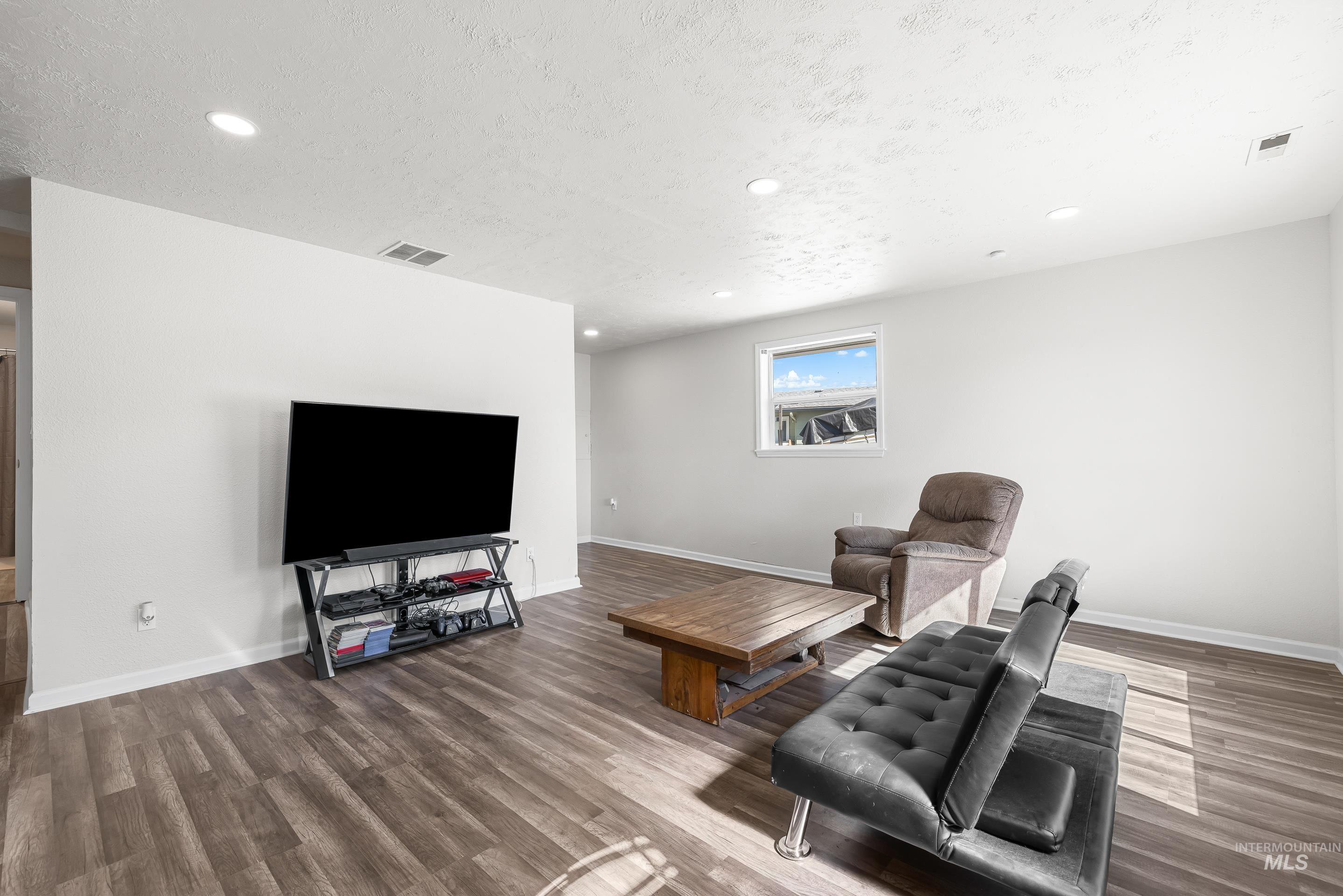 10294 West Fox Ridge Drive Boise, ID 83709 - Photo 7 of 50 Living area with dark wood-style flooring, recessed lighting, and a textured ceiling