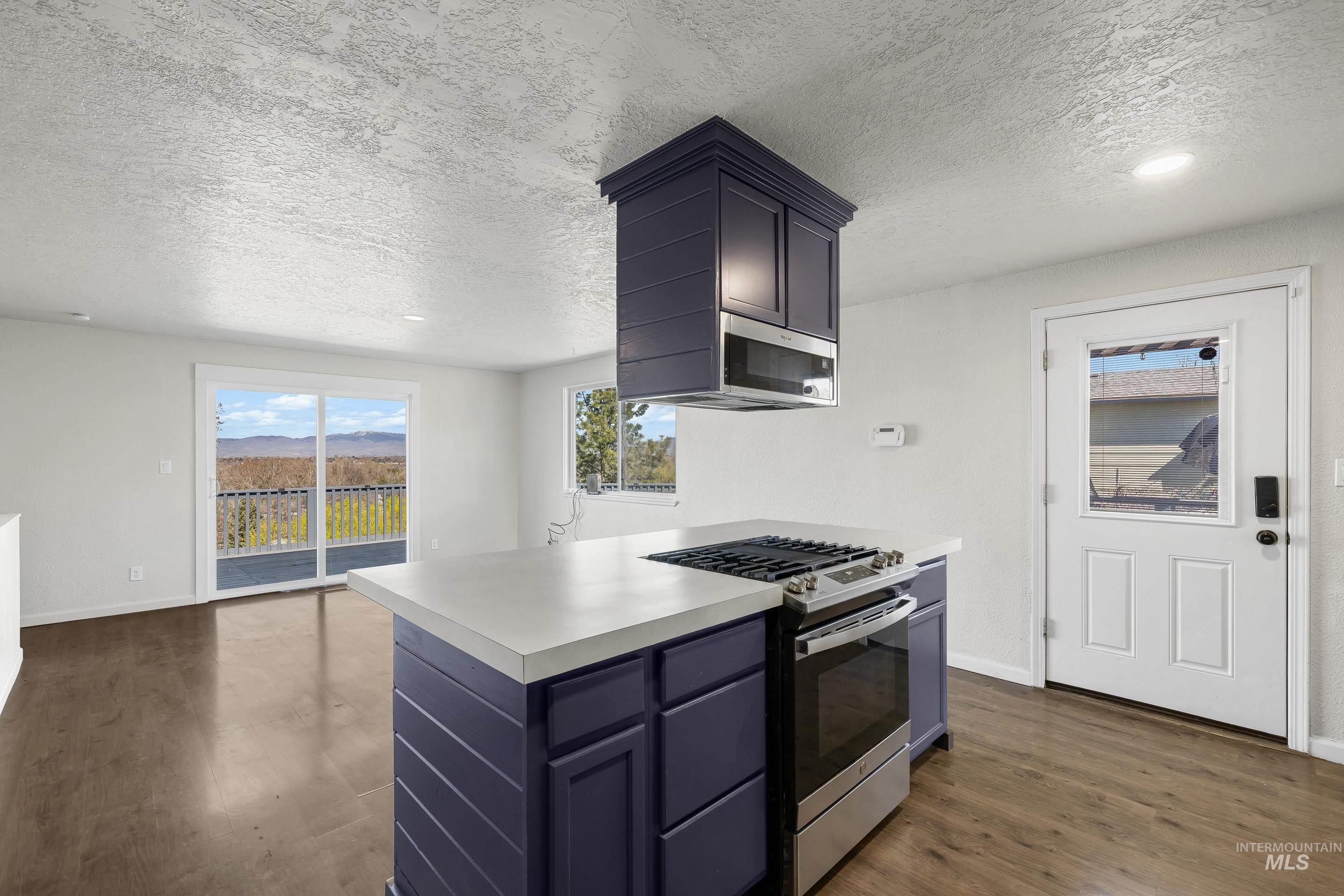 10294 West Fox Ridge Drive Boise, ID 83709 - Photo 49 of 50 Kitchen with stainless steel range with gas cooktop, light countertops, a textured ceiling, dark wood finished floors, and open floor plan