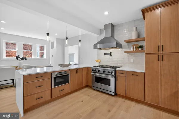 a large white kitchen with stainless steel appliances granite countertop a lot of cabinets and wooden floor