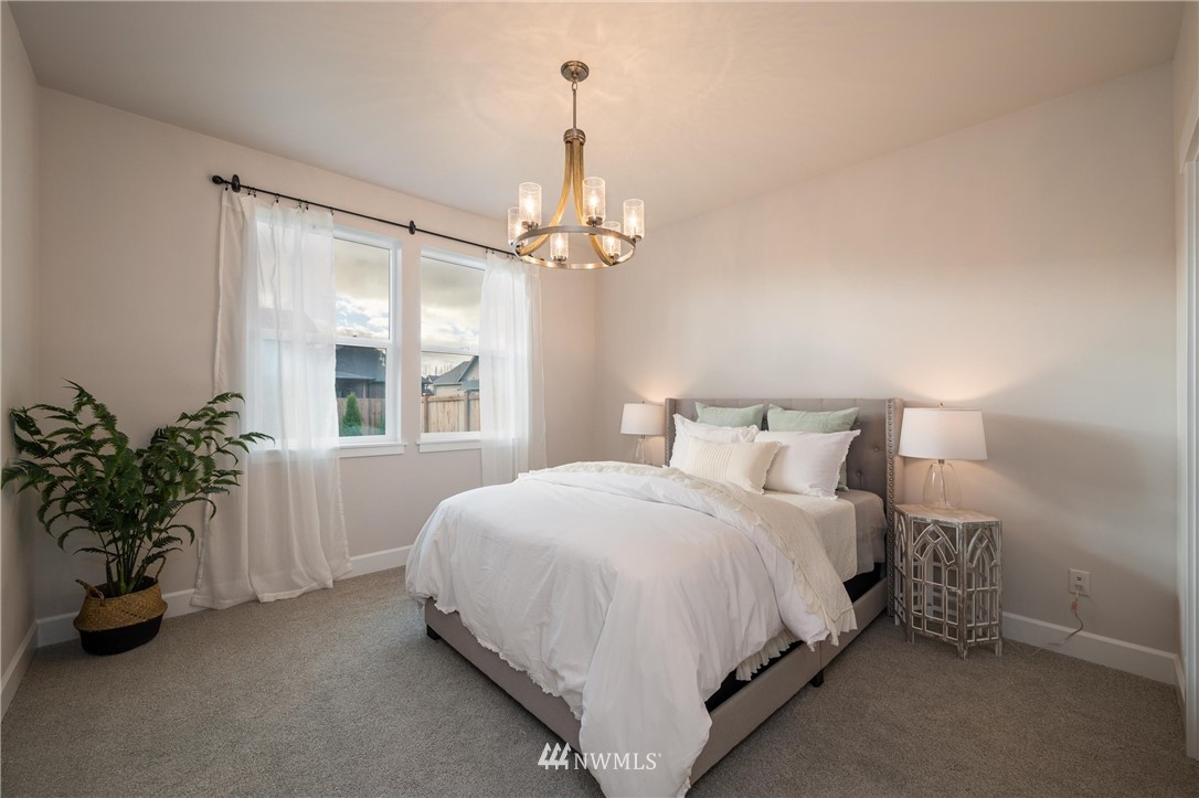 1411 Woods Point Loop Ferndale, WA 98248 - Photo 14 of 31 a bedroom with a bed and a chandelier