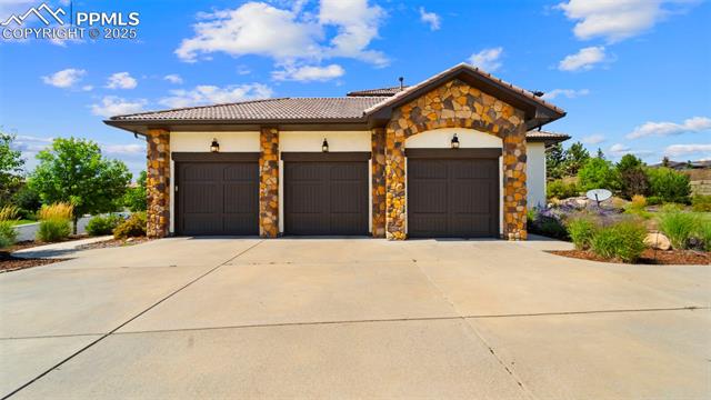 13625 Random Ridge View Colorado Springs, CO 80921 - Photo 39 of 50 Mediterranean / spanish home with concrete driveway, stone siding, a garage, a tiled roof, and stucco siding