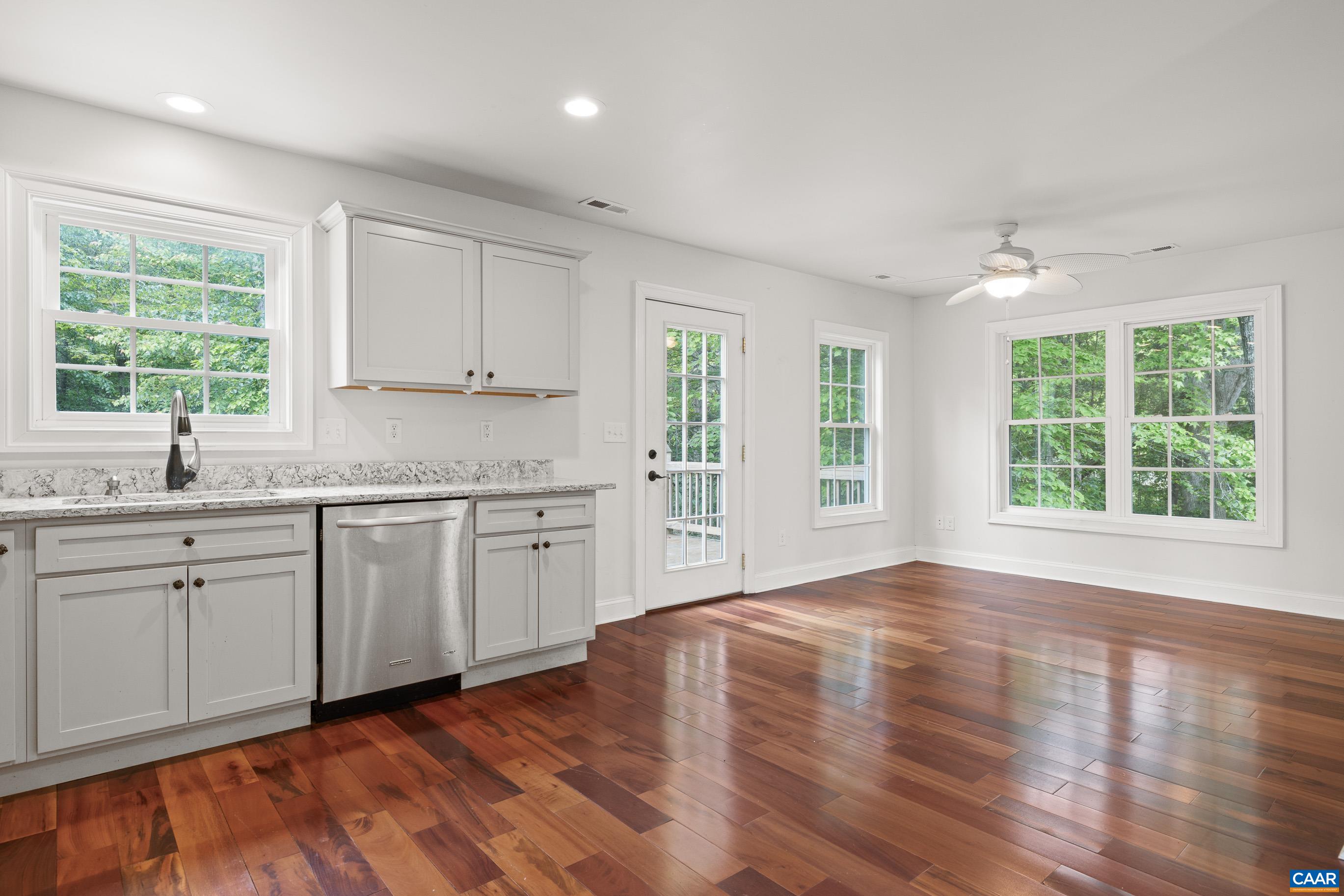 7325 3 Notch Road Louisa, VA 23093 - Photo 60 of 65 a open kitchen with granite countertop a stove a sink white cabinets and wooden floor next to a window