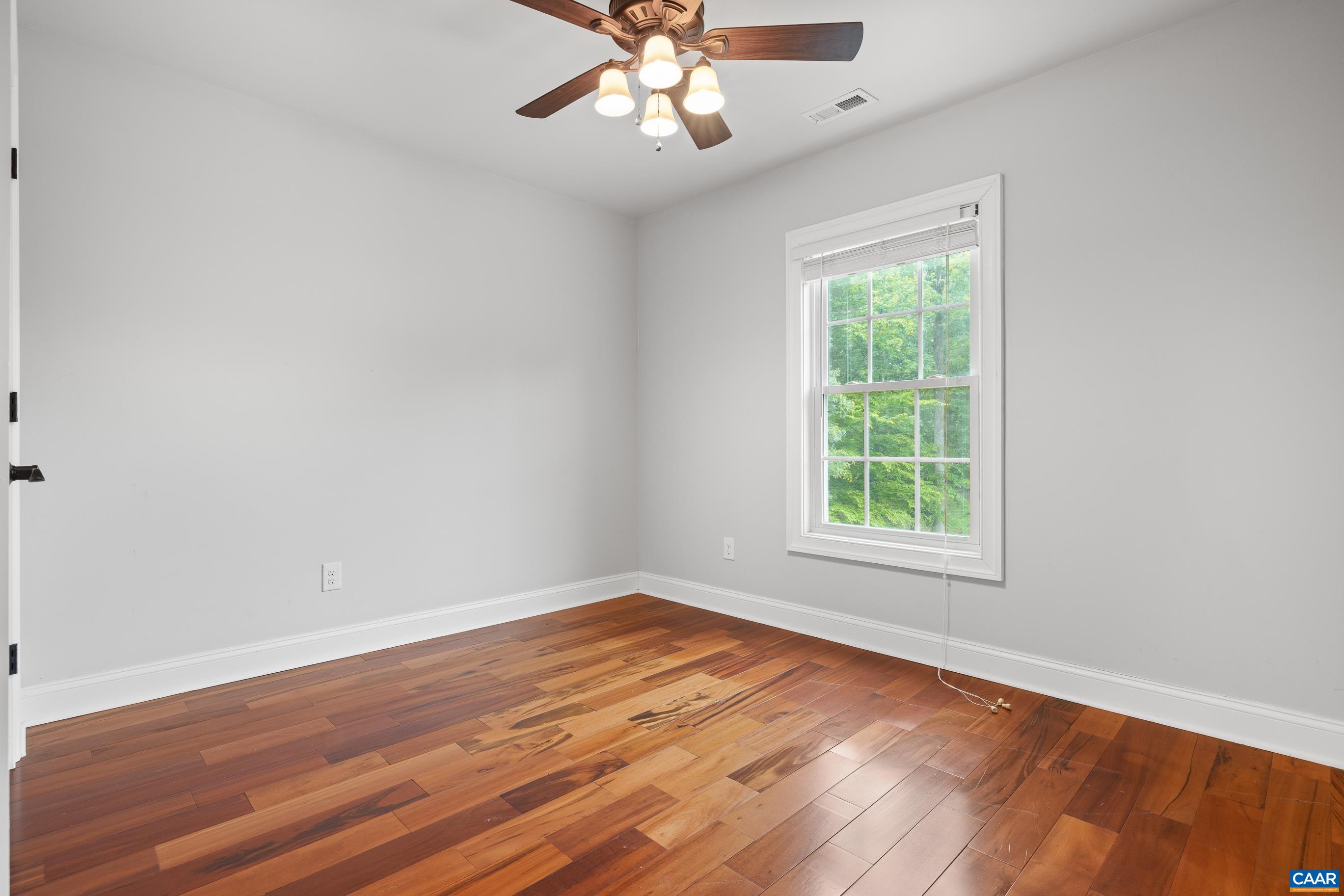 7325 3 Notch Road Louisa, VA 23093 - Photo 62 of 65 an empty room with wooden floor chandelier fan and windows
