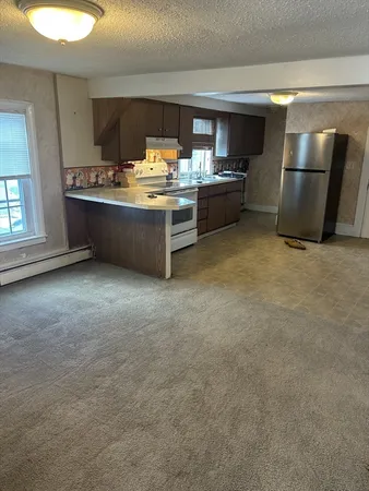 a room with stainless steel appliances a sink a stove a refrigerator a washer dryer and white cabinets