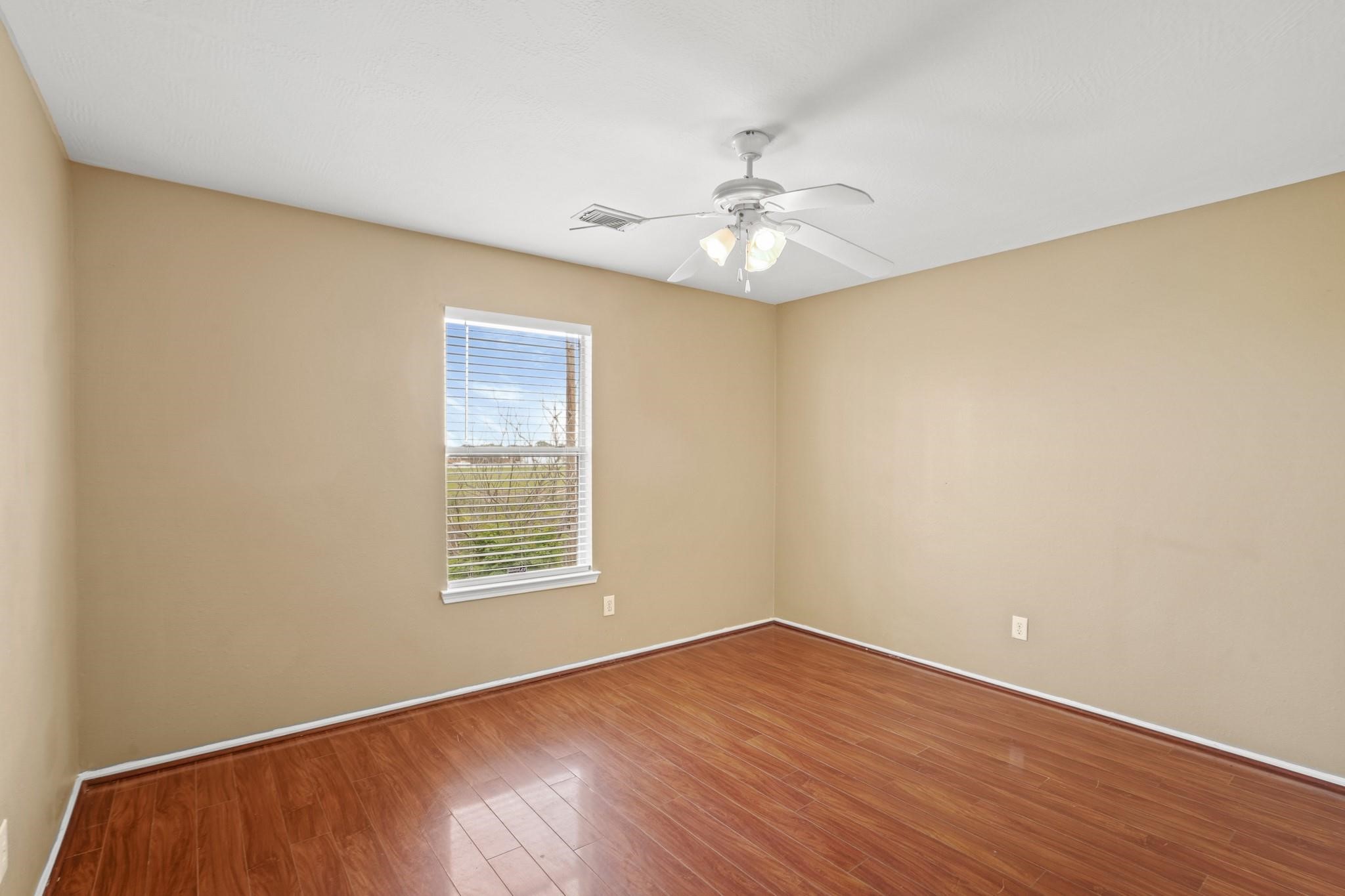 5003 East Parma Drive Rosenberg, TX 77471 - Photo 13 of 25 an empty room with wooden floor chandelier fan and windows
