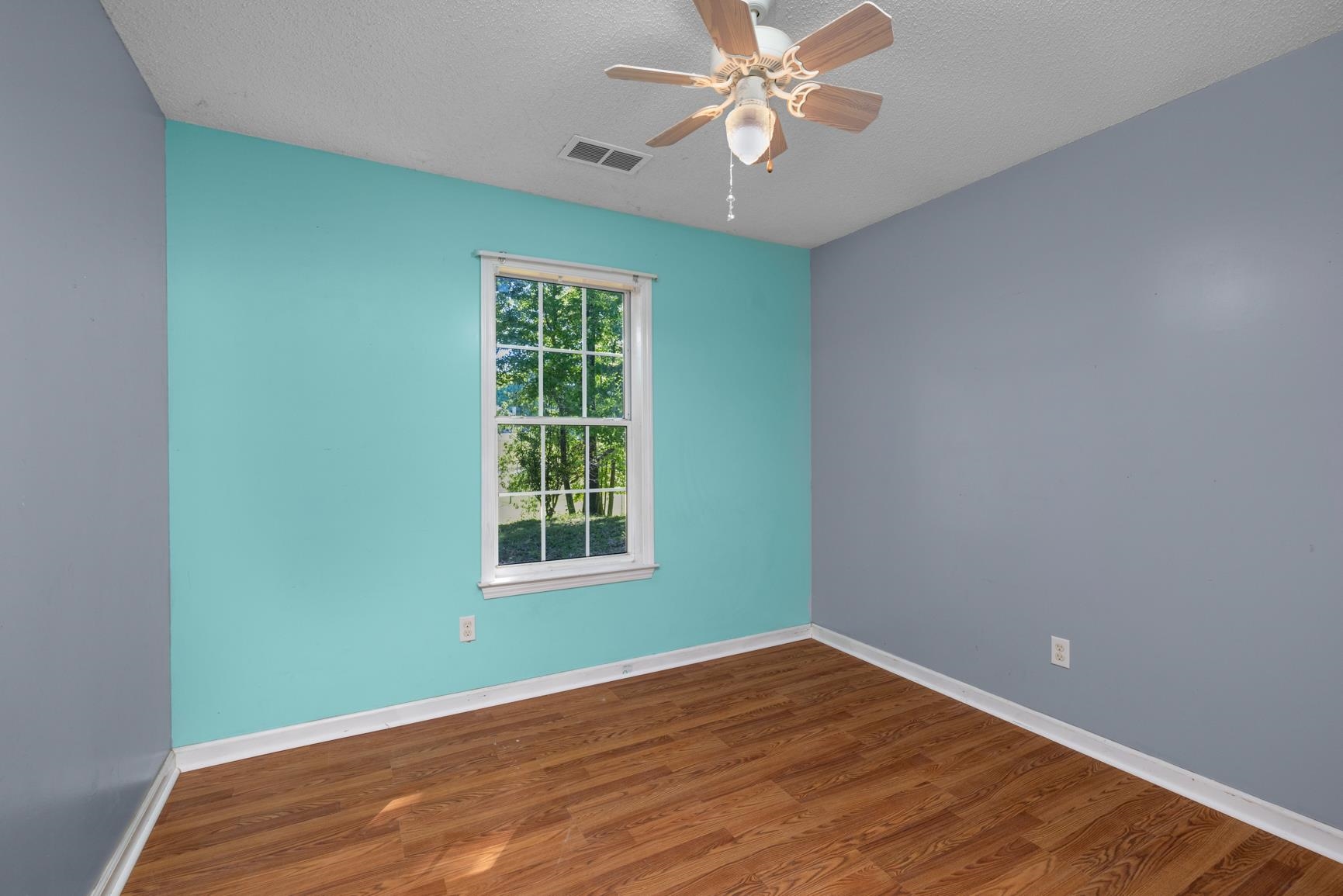 366 Adkins Road Burlison, TN 38015 - Photo 12 of 20 Room featuring wood-finish flooring, a double-hung window, a ceiling fan with light fixture, and contrasting wall colors