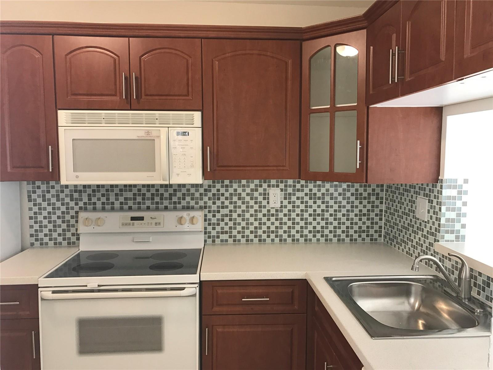 10053 Winding Lake Road, Unit 104 Sunrise, FL 33351 - Photo 2 of 44 a kitchen with granite countertop a sink a stove and cabinets