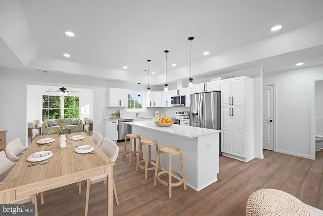 a large white kitchen with stainless steel appliances granite countertop a large center island a stove a refrigerator and a sink