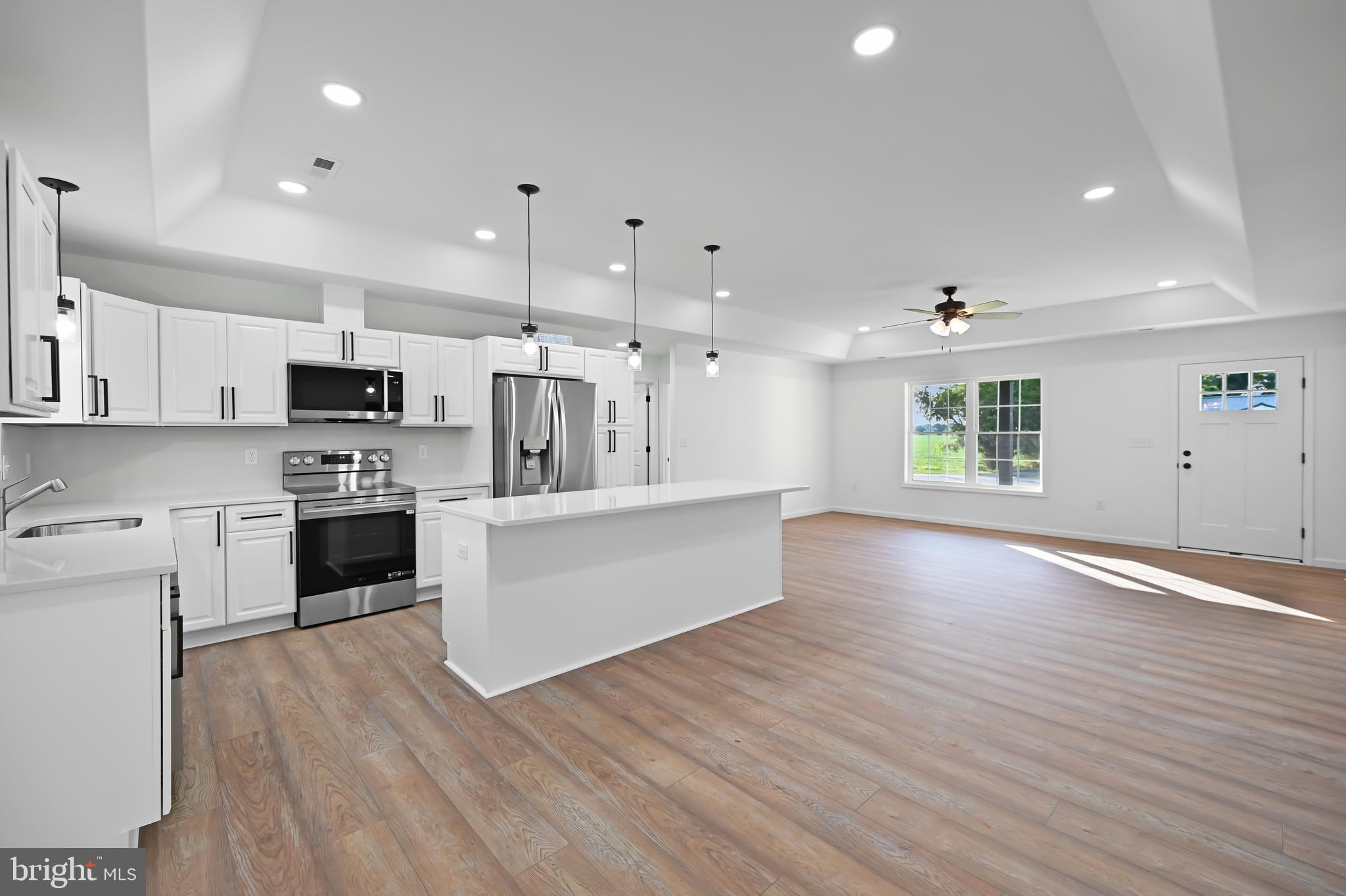23180 Slaughter Neck Road Lincoln, DE 19960 - Photo 15 of 29 a large white kitchen with stainless steel appliances granite countertop a stove a sink a refrigerator white cabinets and wooden floor
