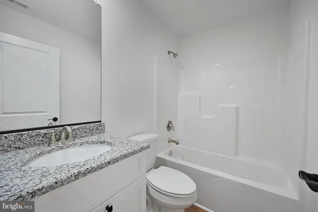 a bathroom with a granite countertop sink a toilet and shower