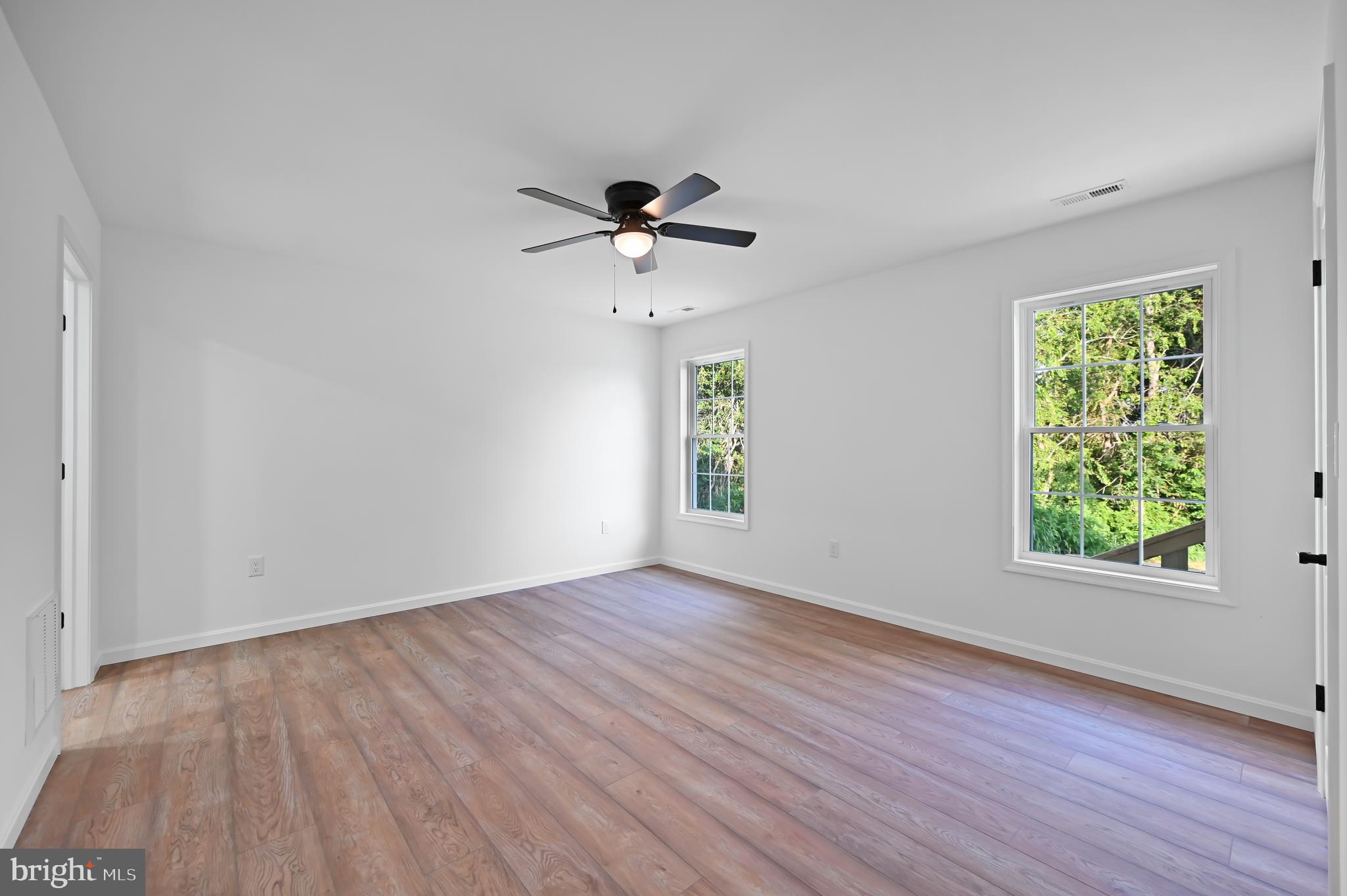 23180 Slaughter Neck Road Lincoln, DE 19960 - Photo 22 of 29 an empty room with wooden floor chandelier fan and windows