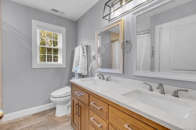 a bathroom with a granite countertop toilet sink and mirror