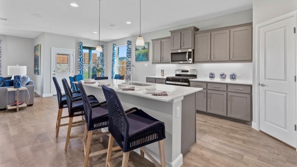 a kitchen with stainless steel appliances kitchen island granite countertop a table chairs sink and cabinets