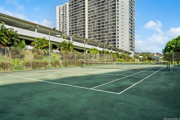 a view of a tennis ground with large trees