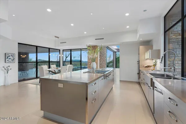 a large white kitchen with a large window and stainless steel appliances