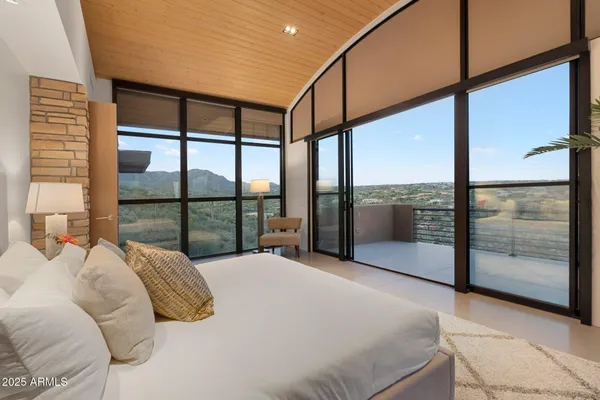 a bedroom with a large window and a balcony