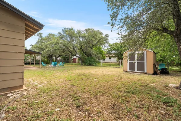 a backyard of a house with large trees and plants