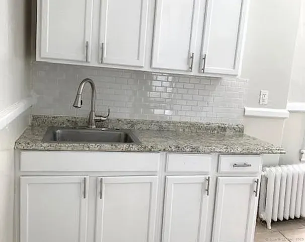 a kitchen with granite countertop white cabinets and a sink