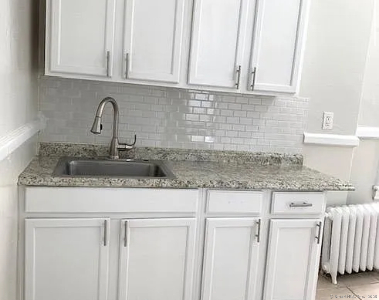 a kitchen with granite countertop white cabinets and a sink
