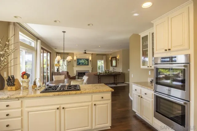 a kitchen with stainless steel appliances kitchen island granite countertop a stove a sink and white cabinets with wooden floor