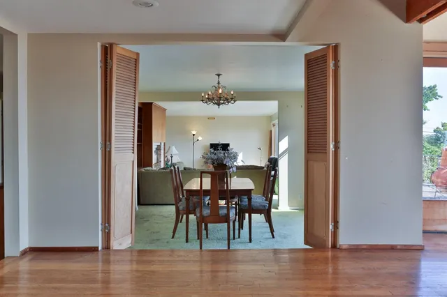 a dining hall with couches a flat tv screen and a dining table with the kitchen view