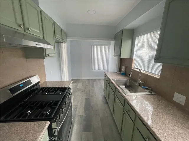 a kitchen with granite countertop a sink stove and cabinets