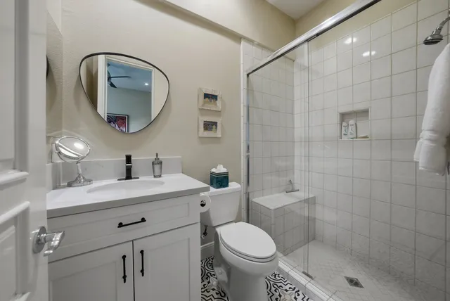 a bathroom with a toilet sink vanity granite and a mirror