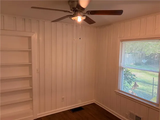 a view of empty room with wooden floor and fan