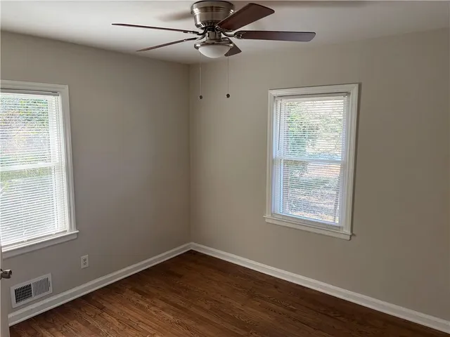 an empty room with wooden floor closet and windows