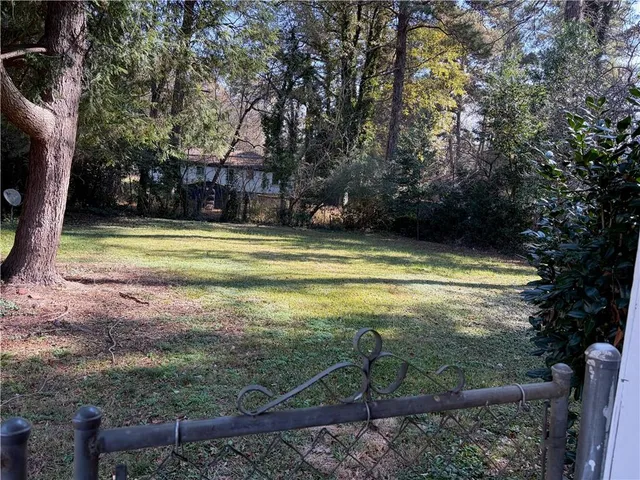 a view of a swimming pool with a yard and large trees