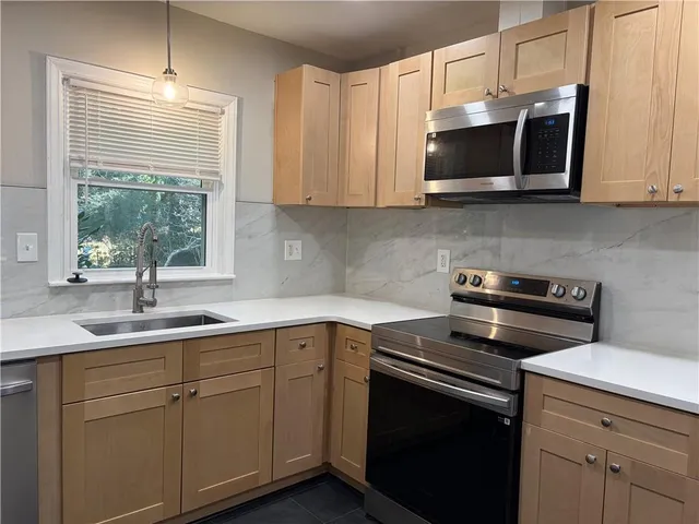 a kitchen with stainless steel appliances granite countertop a sink a stove a microwave and wooden cabinets