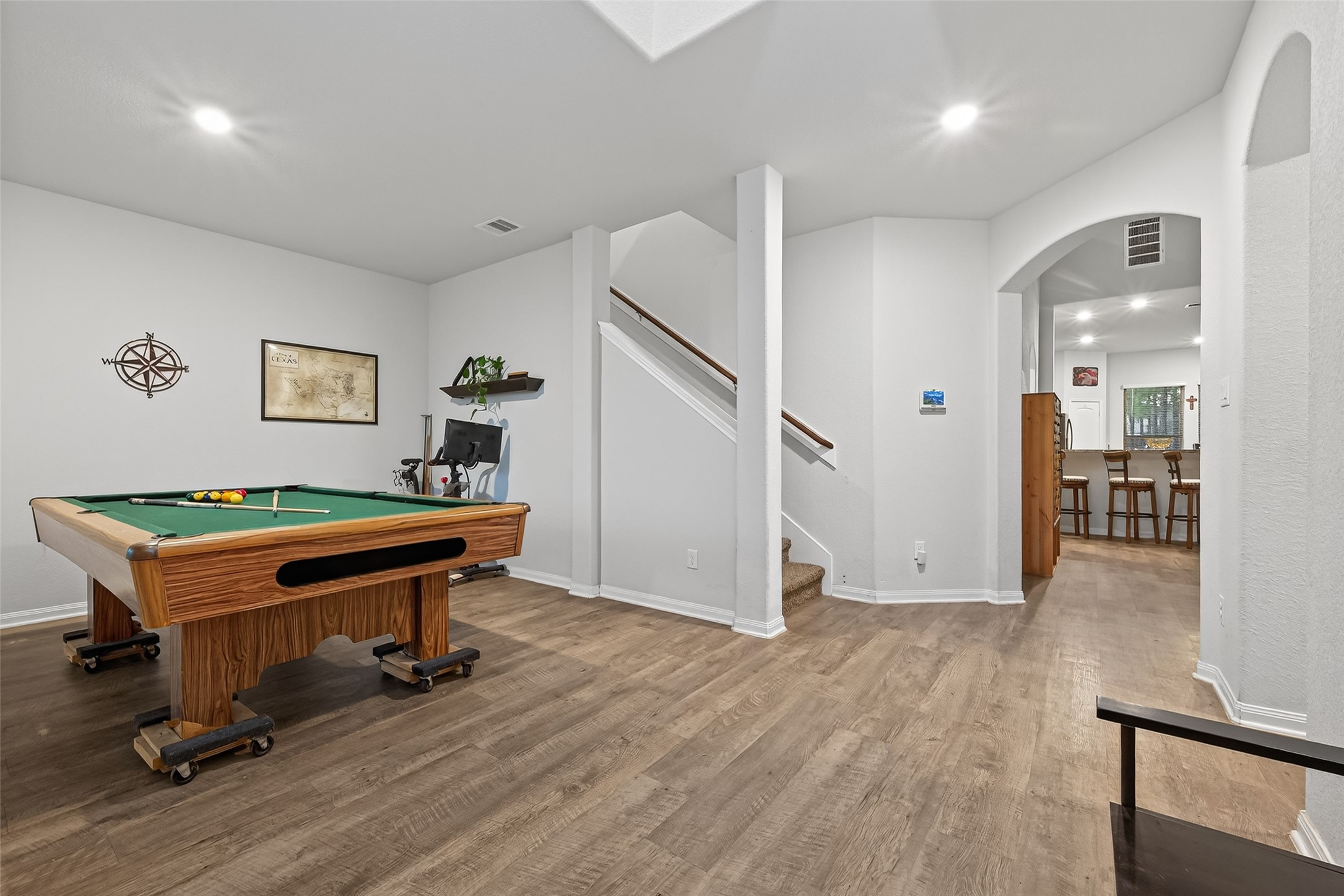16601 Crosby Street Conroe, TX 77303 - Photo 7 of 50 Spacious flex room with wood-look flooring, neutral tones, and an open layout that flows seamlessly into the kitchen and living areas—perfect for a game room, office, or second living space.