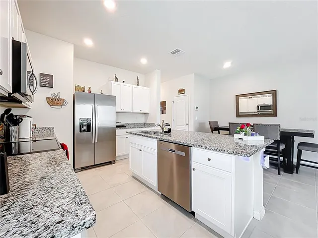 a kitchen with stainless steel appliances kitchen island granite countertop a refrigerator and a stove top oven