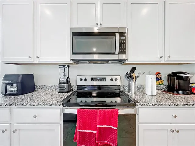 a kitchen with granite countertop a stove top oven microwave and cabinets