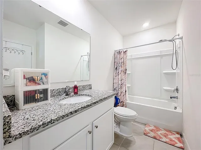 a bathroom with a granite countertop sink a toilet and shower