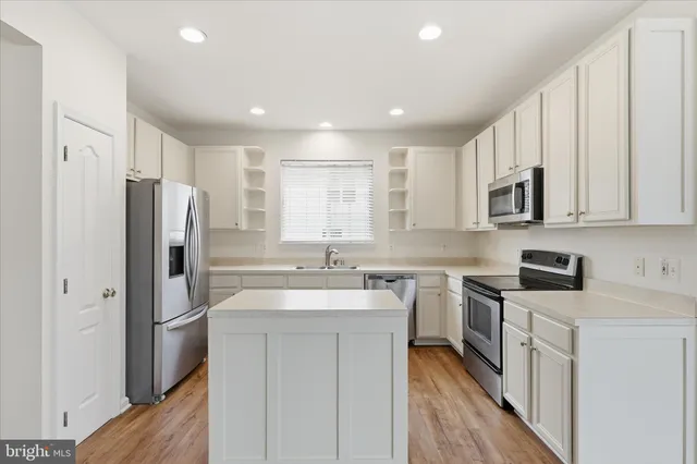 a kitchen with stainless steel appliances a sink stove refrigerator and cabinets